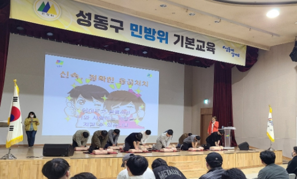 민방위 기본교육 중인 사진이다. 사람들이 모여서 심폐소생과 관련된 교육을 실전처럼 시연하고 있다.